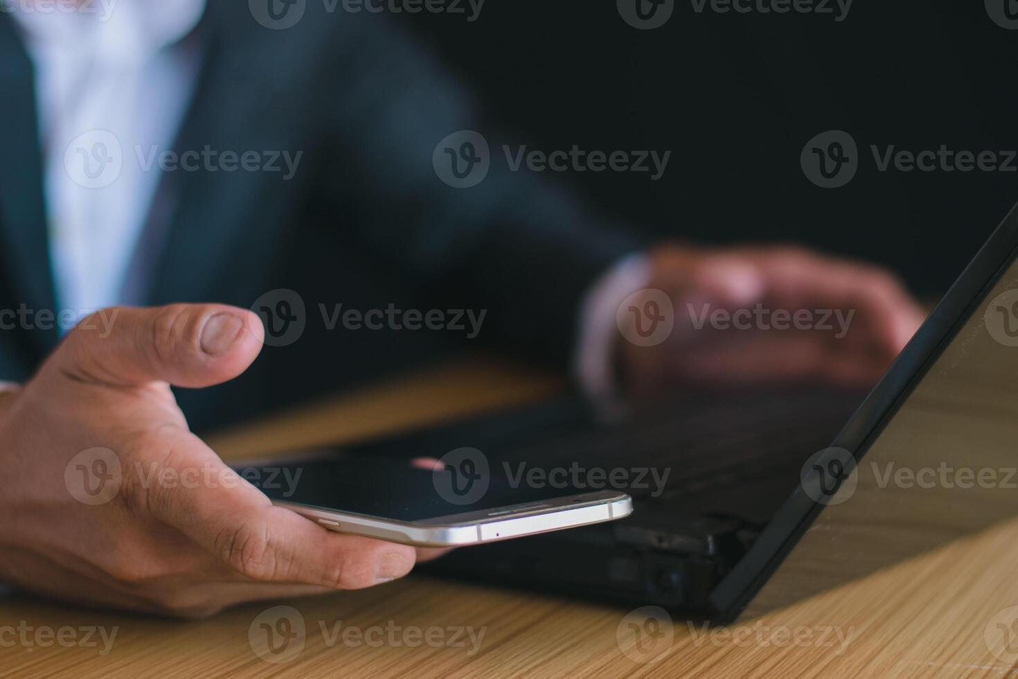 detailopname van een zakenman werken met een notitieboekje computer en gebruik makend van een mobiel telefoon, smartphone, chatten in de kantoor. foto