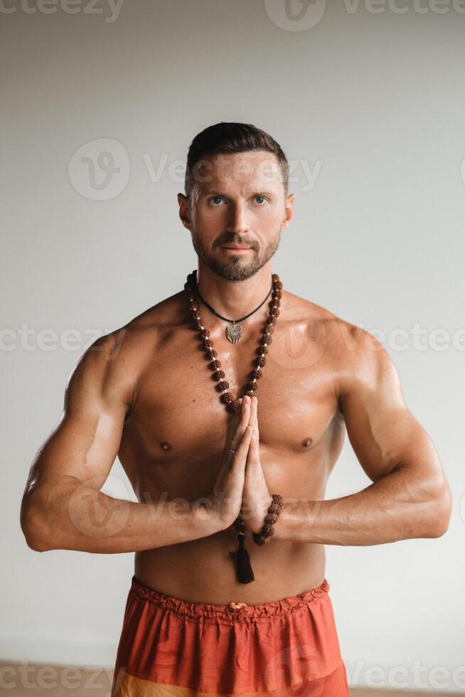 een gespierd Mens met een kaal torso en een amulet is staand in de kamer foto