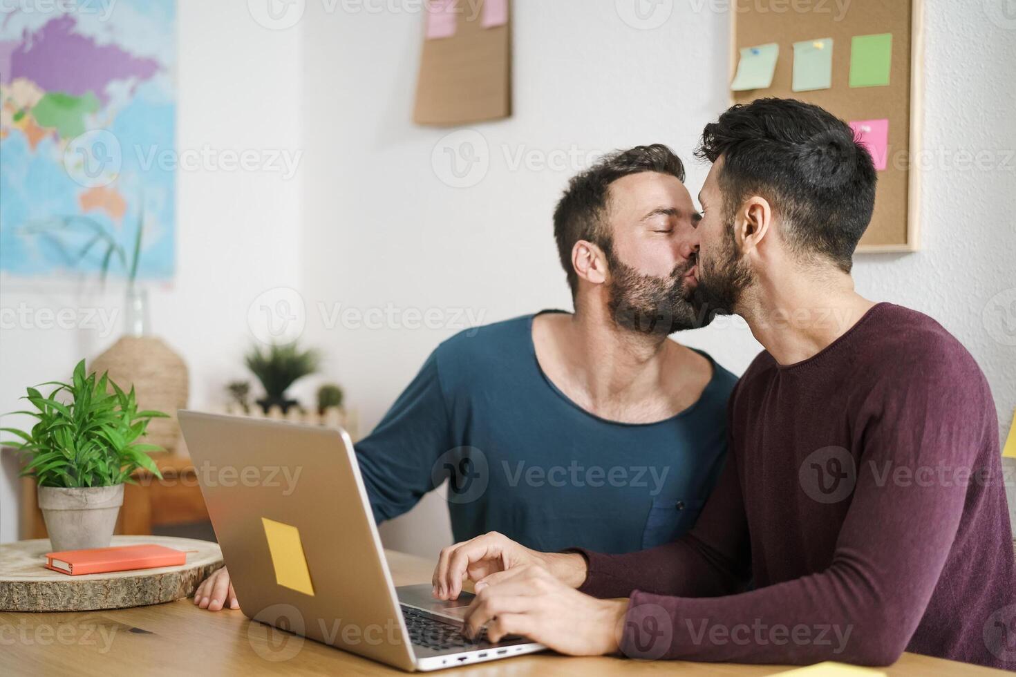 gelukkig homo paar zoenen terwijl gebruik makend van laptop in leven kamer Bij huis - lgbt liefde en technologie concept foto