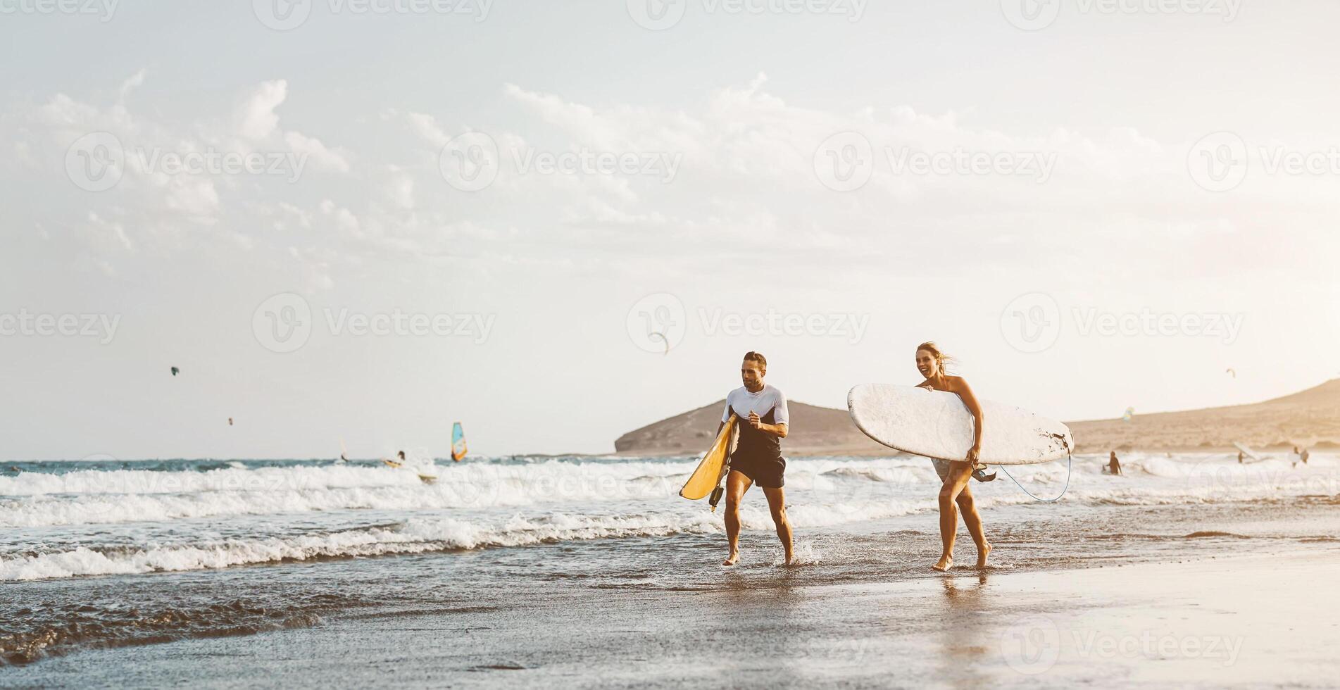 surfer paar rennen lang zee kust klaar naar surfen Aan hoog golven - sportief vrienden hebben pret gedurende surfing dag in oceaan - extreem sport Gezondheid levensstijl mensen concept foto