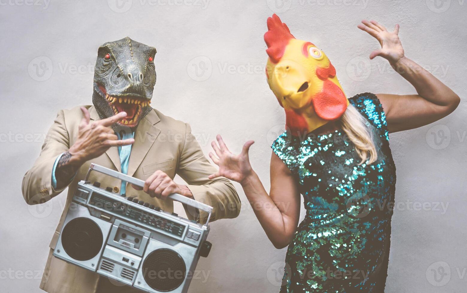 gek senior paar vervelend kip en t-rex masker terwijl dansen buitenshuis - volwassen modieus mensen hebben pret vieren en luisteren muziek- met boombox - absurd concept van maskerade grappig vakantie foto