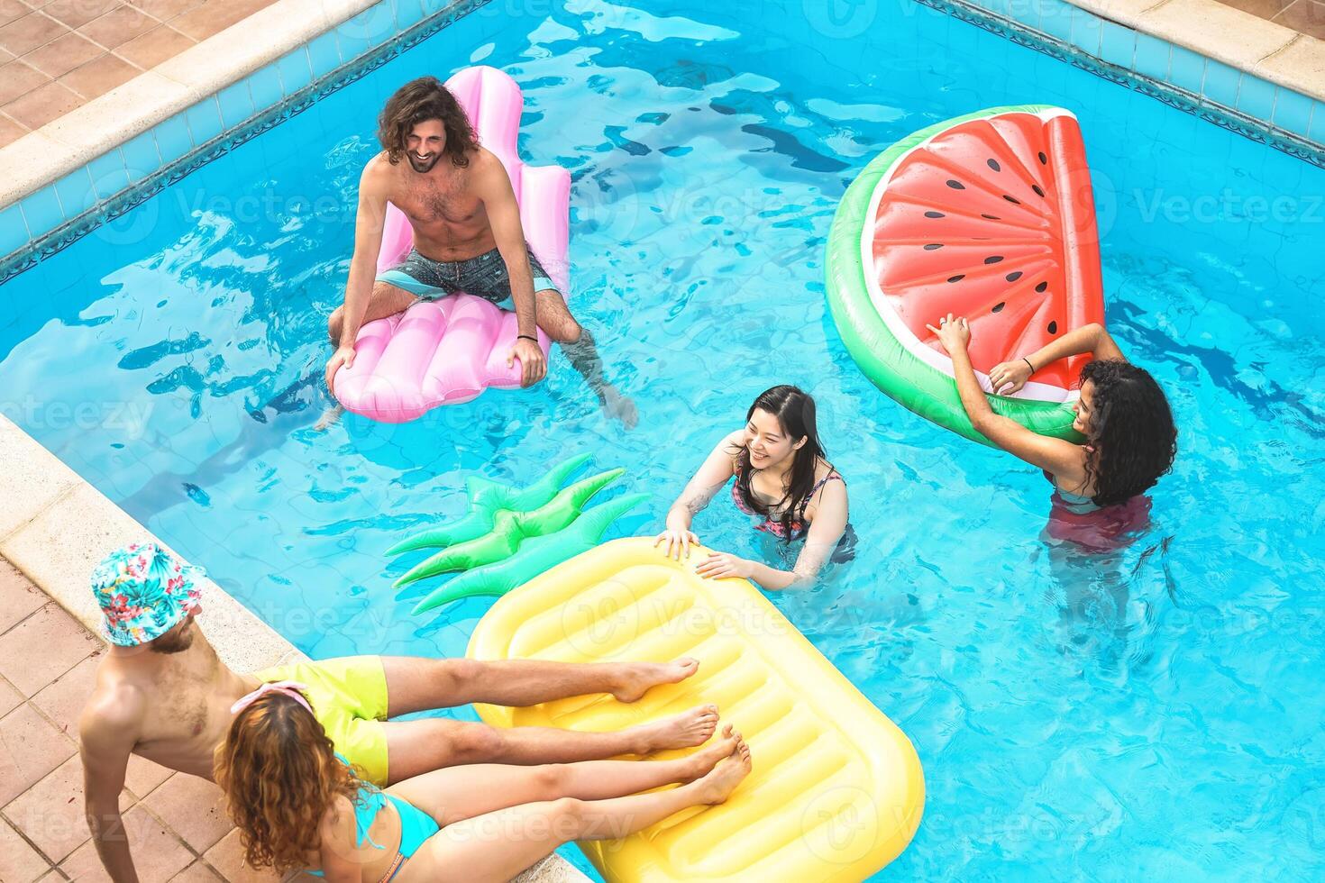groep gelukkig vrienden genieten van zomer dag in zwemmen zwembad met opblaasbaar - jong multiraciaal mensen hebben pret in exclusief toevlucht hotel - jeugd vakantie levensstijl concept foto