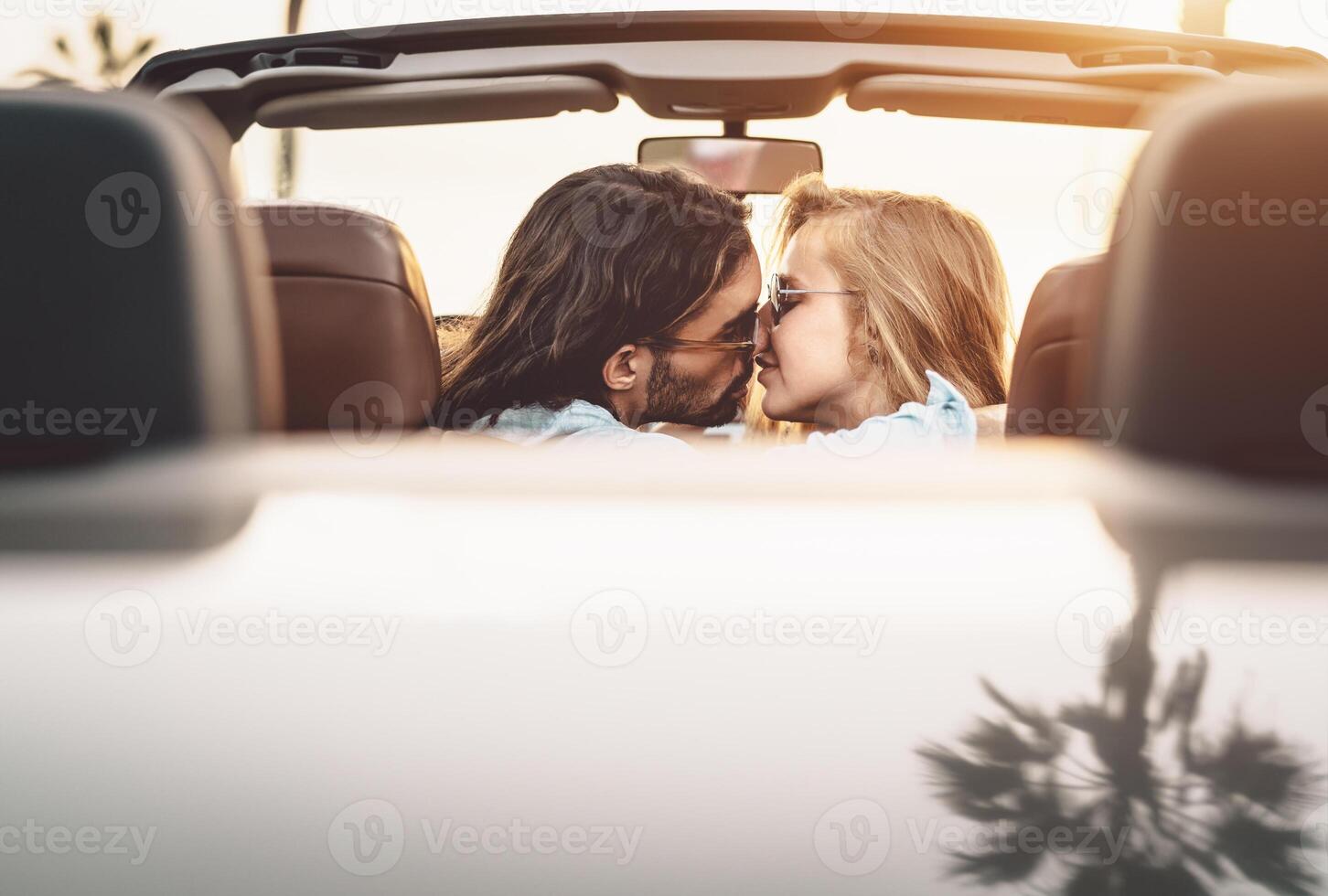 gelukkig paar zoenen in converteerbaar auto - romantisch mensen hebben inschrijving moment gedurende weg reis in tropisch stad - liefde verhouding en jeugd vakantie levensstijl concept foto