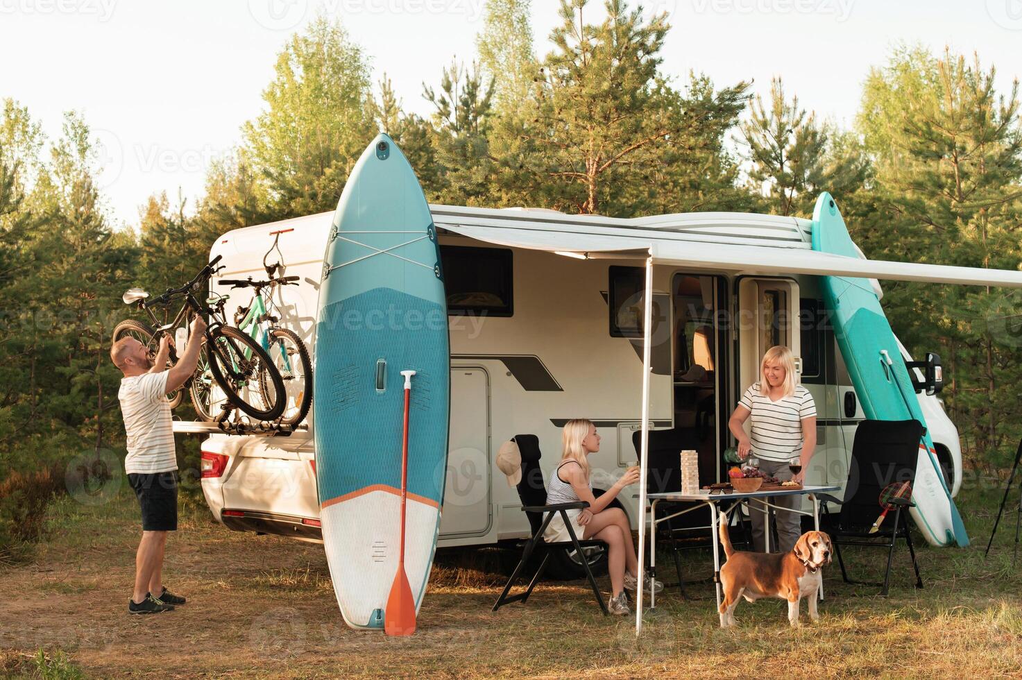 een gelukkig familie is resting dichtbij in de buurt hun camper in de Woud foto