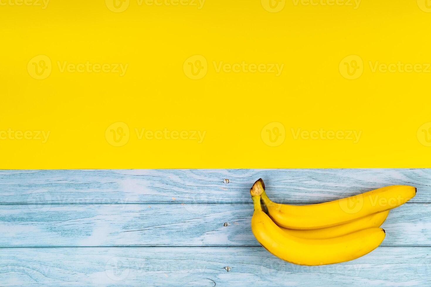 geel bananen liggen Aan een blauw houten achtergrond en een geel achtergrond foto