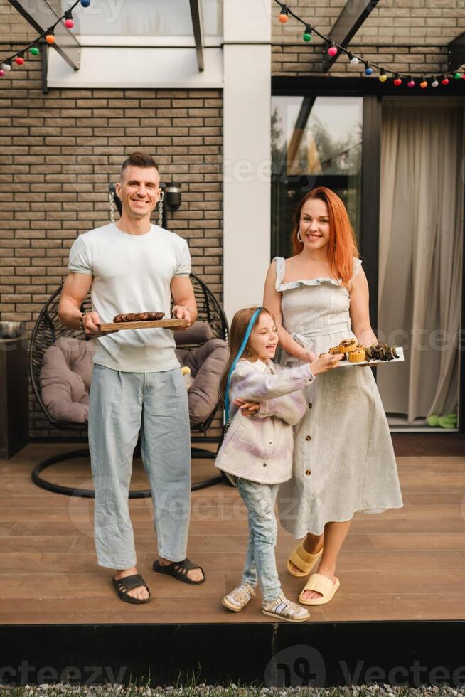 een gelukkig familie heeft bereid lunch en zullen eten Bij hun huis. portret van een familie met voedsel in hun handen foto