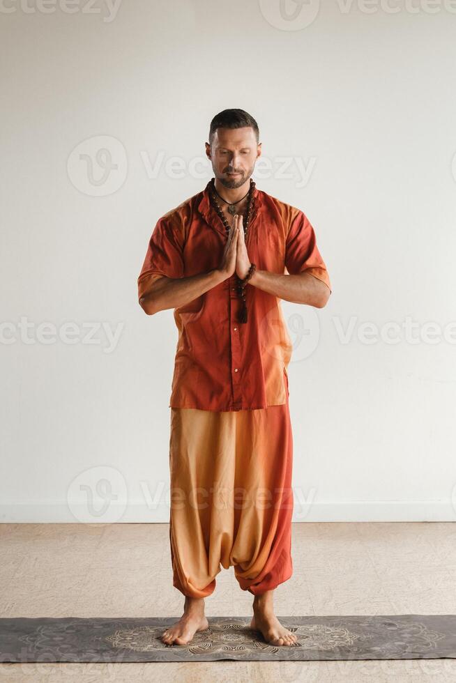 een Mens in een oranje pak doet yoga in een geschiktheid kamer. de concept van Gezondheid foto