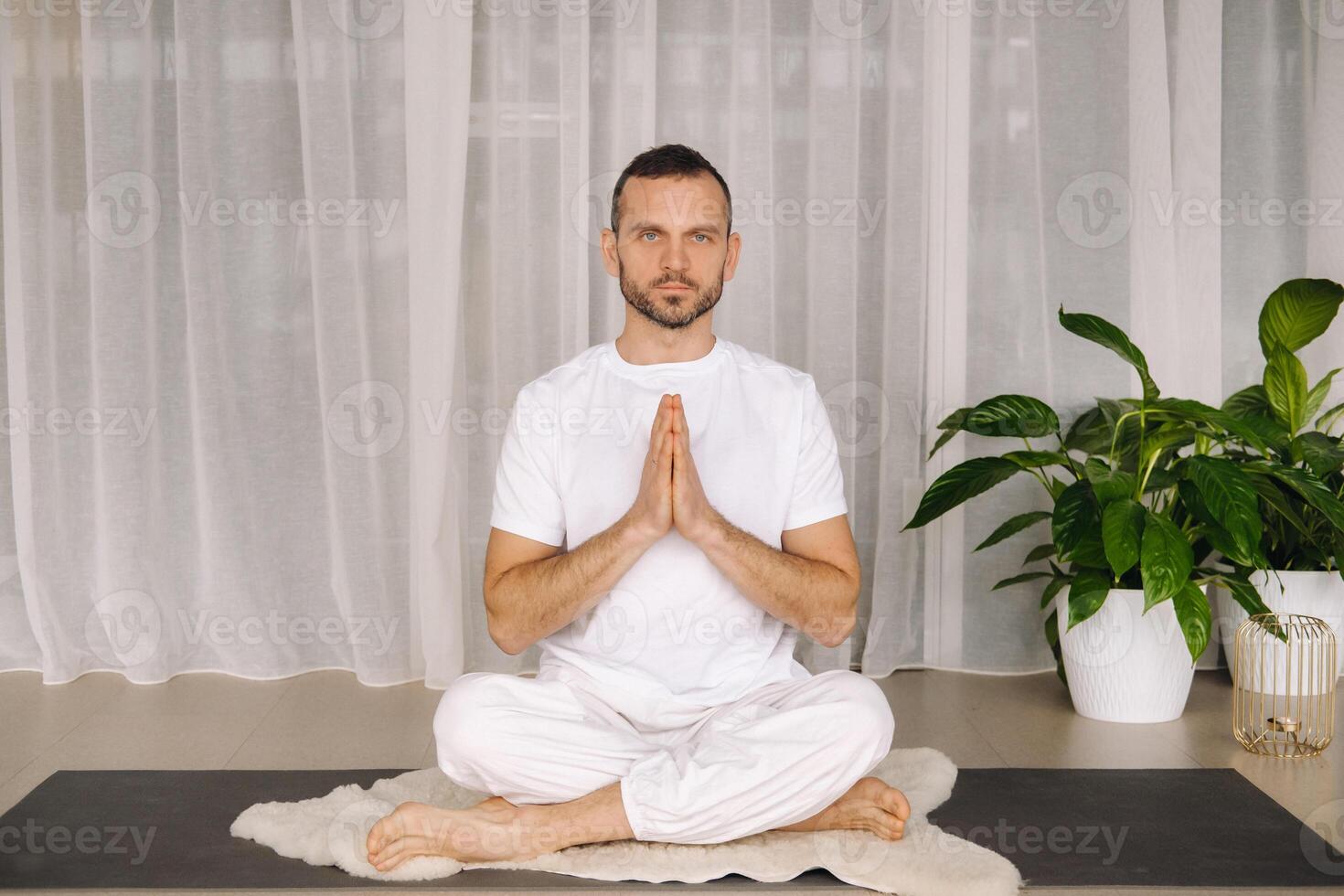 een Mens in wit sportkleding is aan het doen yoga met een geschiktheid kamer. de concept van een gezond levensstijl foto