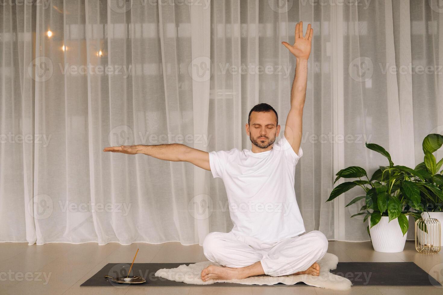 een Mens in wit sportkleding is aan het doen yoga met een geschiktheid kamer. de concept van een gezond levensstijl foto