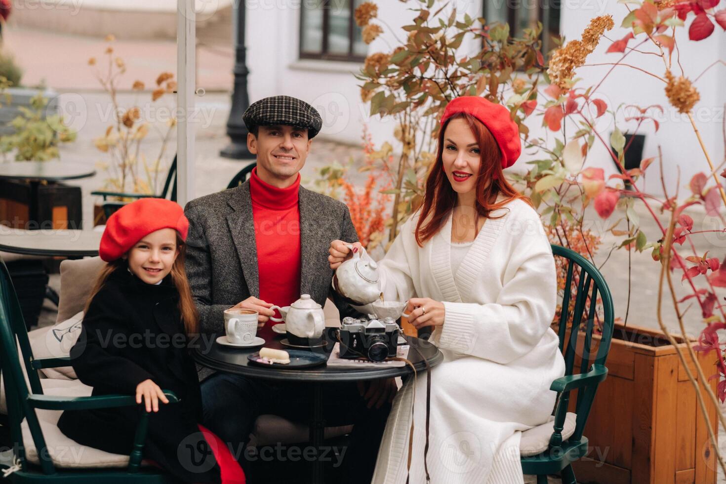 een elegant familie verzameld samen in een cafe Aan de straat. mama, pa, weinig dochter drinken thee, eten taarten. ze zijn gelukkig samen. de concept van een gelukkig familie avondeten foto