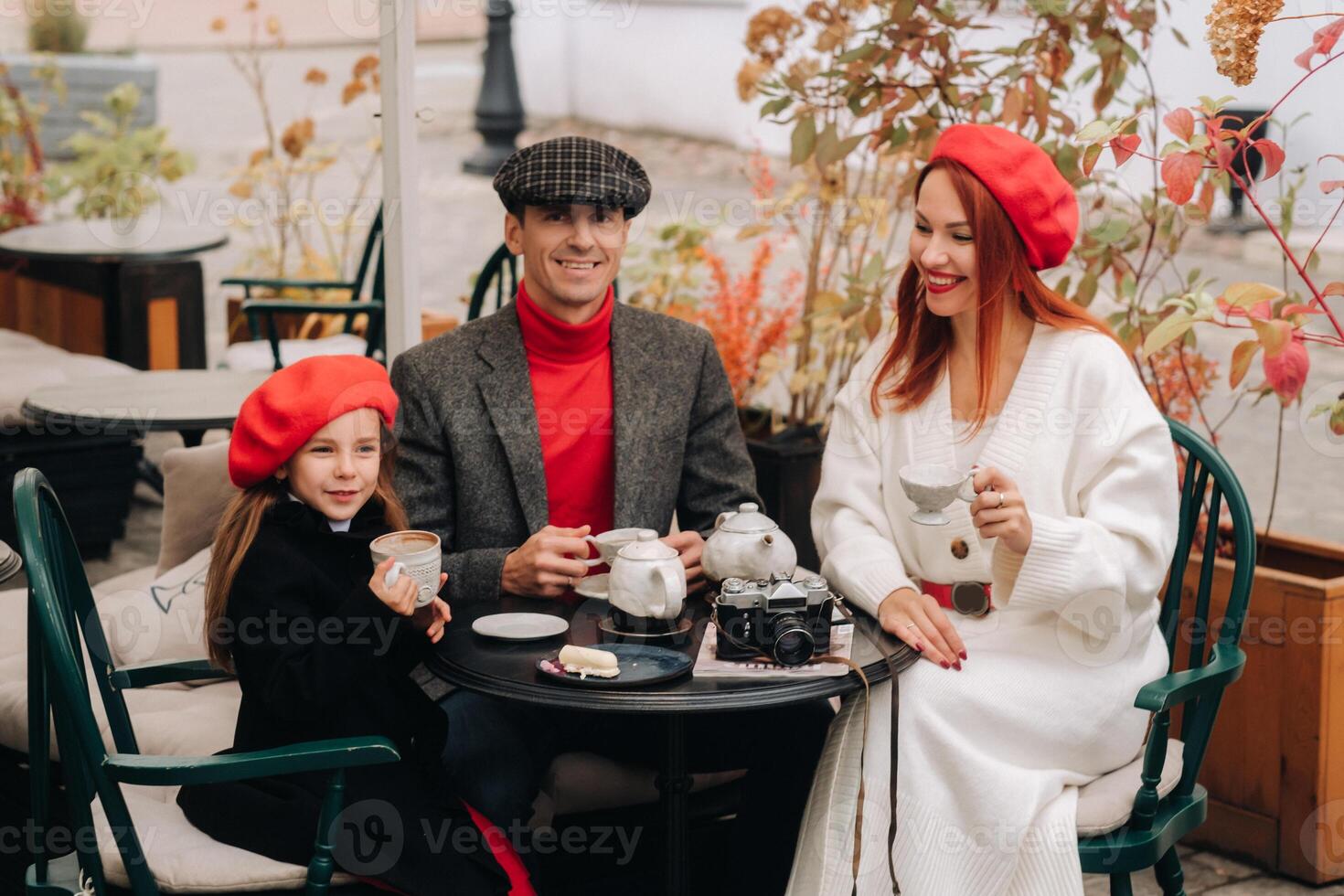 een elegant familie verzameld samen in een cafe Aan de straat. mama, pa, weinig dochter drinken thee, eten taarten. ze zijn gelukkig samen. de concept van een gelukkig familie avondeten foto