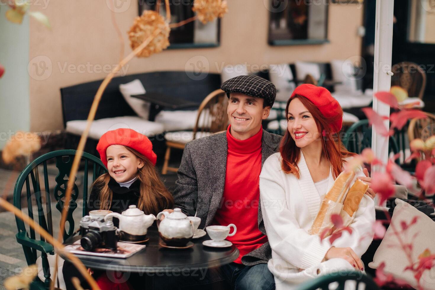 een elegant familie verzameld samen in een cafe Aan de straat. mama, pa, weinig dochter drinken thee, eten taarten. ze zijn gelukkig samen. de concept van een gelukkig familie avondeten foto