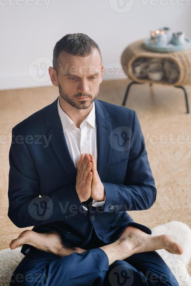 een Mens in een streng pak doet yoga terwijl zittend in een geschiktheid kamer foto