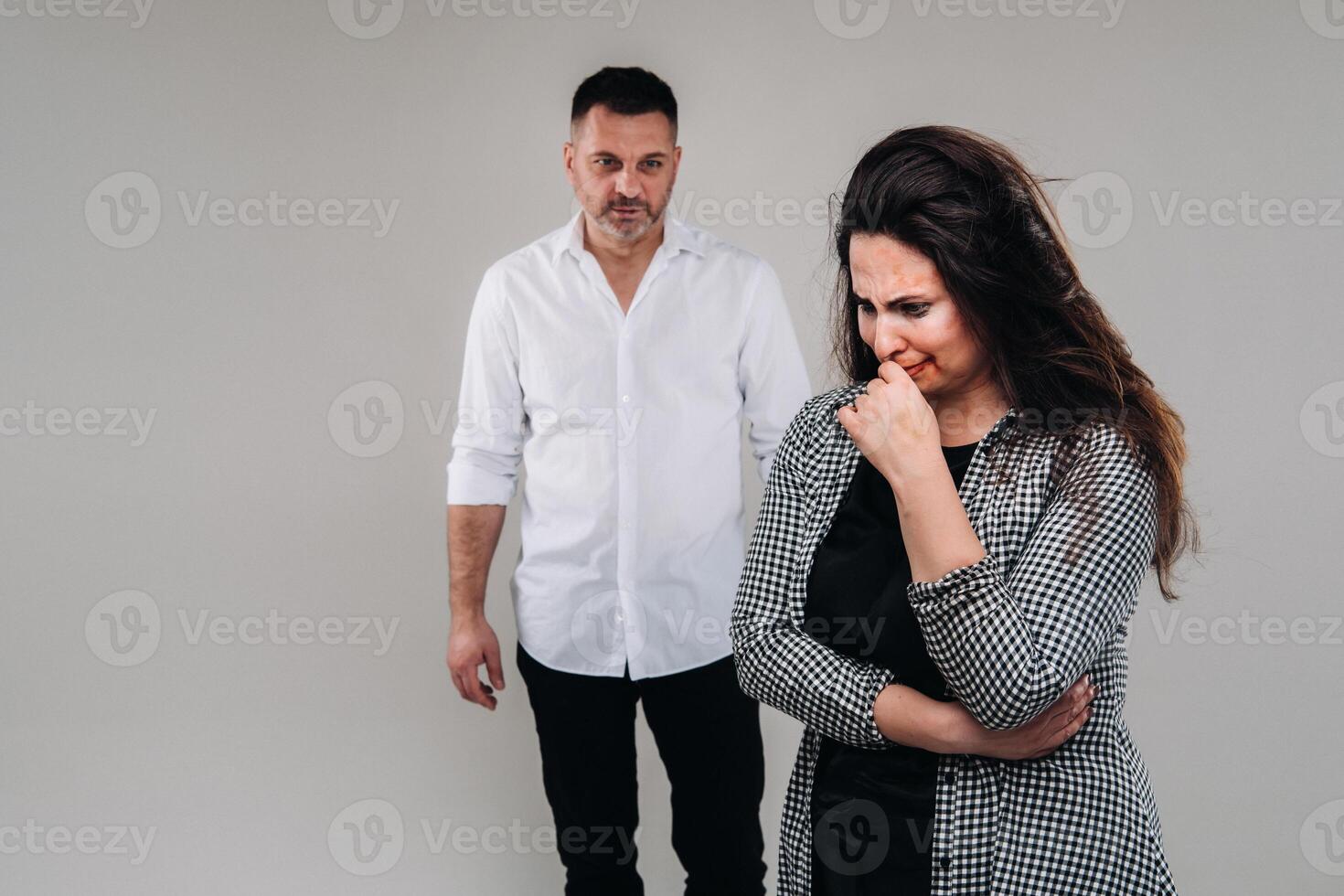 een vrouw geslagen door haar man staand achter haar en op zoek Bij haar agressief. huiselijk geweld foto