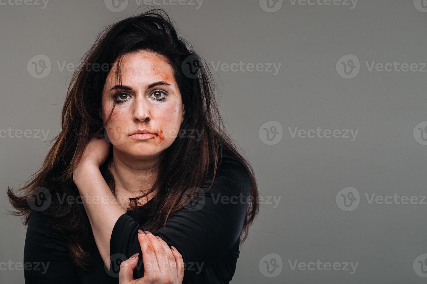 een gehavend vrouw in zwart kleren Aan een geïsoleerd grijs achtergrond. geweld tegen Dames foto