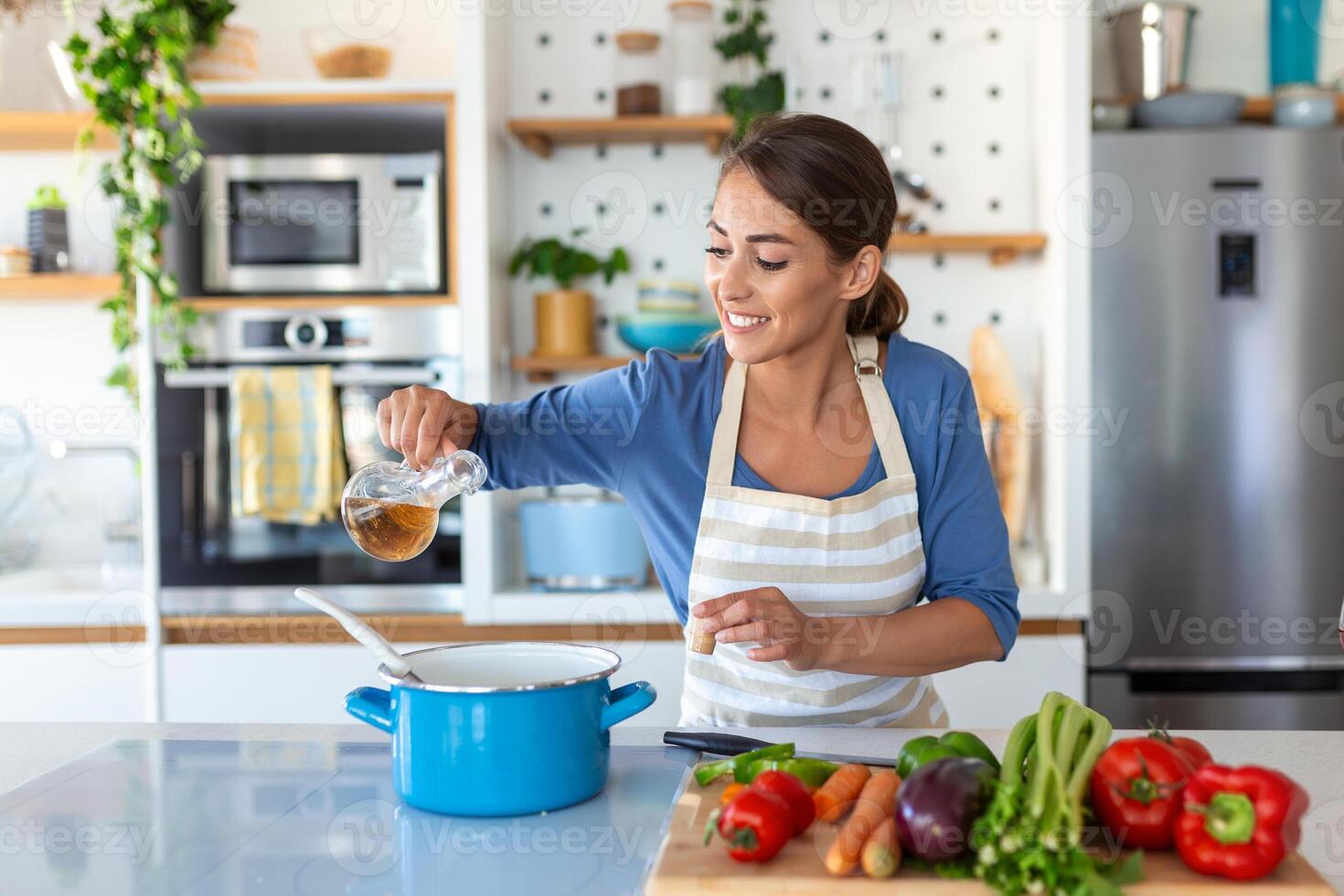 gelukkig jong vrouw Koken proeverij avondeten in een pot staand in modern keuken Bij huis. huisvrouw voorbereidingen treffen gezond voedsel glimlachen . huishouden en voeding. dieet recepten concept foto