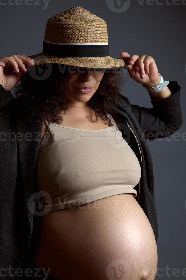 charmant sexy zwanger vrouw met naakt buik, in laatste trimester van zwangerschap, geïsoleerd mode grijs studio achtergrond. foto