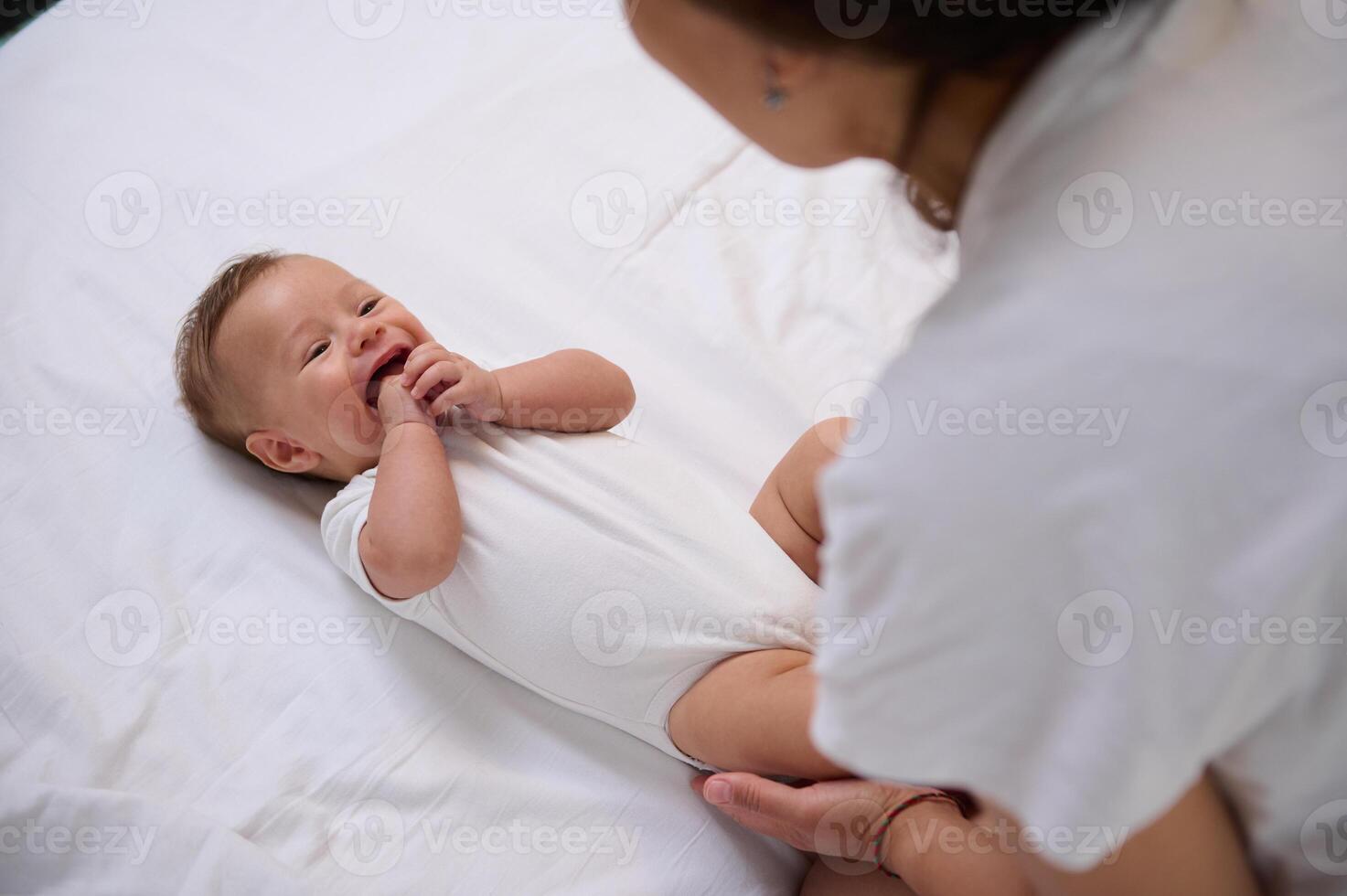 authentiek moeder duurt zorg van haar glimlachen baby jongen 4 maanden oud, gevoel emotioneel verbinding. moederschap laten staan. kinderschoenen foto