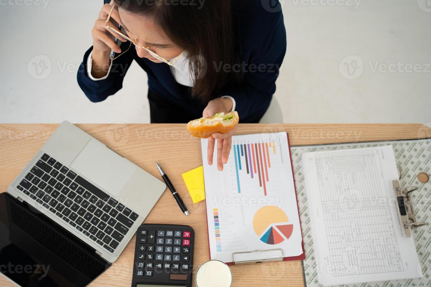 bezig en moe zakenvrouw aan het eten brood en melk voor lunch Bij de bureau kantoor en werken naar leveren financieel verklaringen naar een baas. overwerkt en ongezond voor klaar maaltijden, burn-out concept. foto