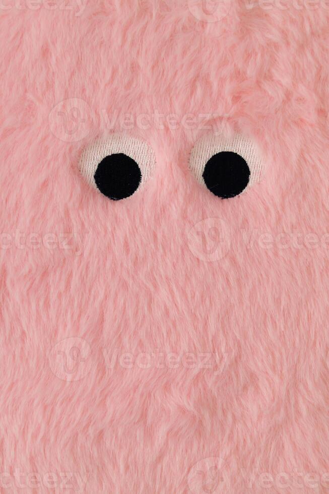 schattig pluizig monster gemaakt met pastel roze faux vacht. minimaal concept. creatief grappig gezicht samenstelling. een origineel peachy roze vacht achtergrond beeld idee. vlak leggen, top van visie. foto