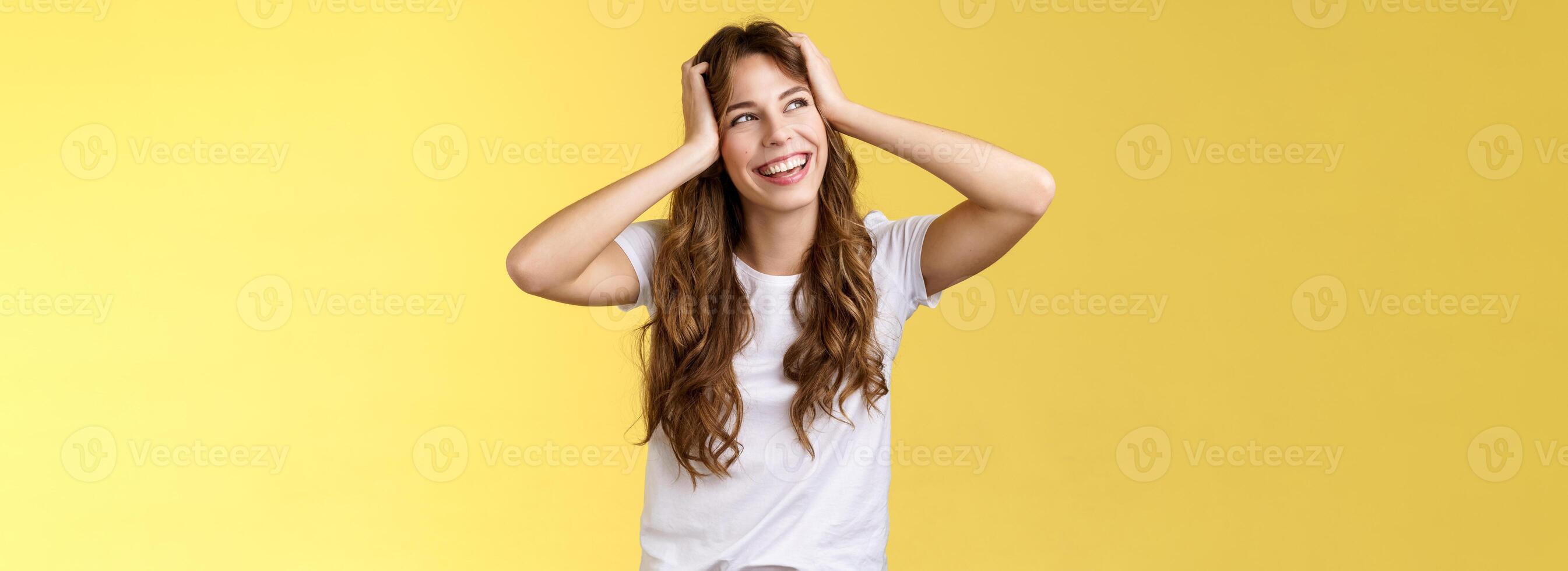 zorgeloos gelukkig aantrekkelijk glimlachen meisje houden hoofd gekruld kapsel beurt weg bovenste links hoek zonnig zomer dag uitstekend Lucky weekends staand geamuseerd opgewonden avonturen begin geel achtergrond foto