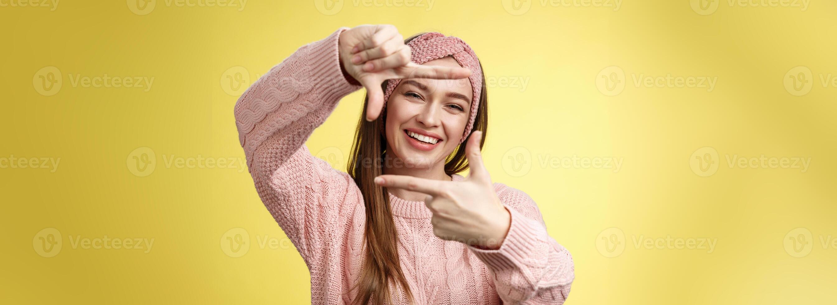 charmant extravert, gelukkig meisje glimlachen vrolijk, maken kader van vingers op zoek door het opgewonden en blij, grijnzend, planning toekomst, afbeelden hoe zetten meubilair, poseren schattig over- geel muur foto