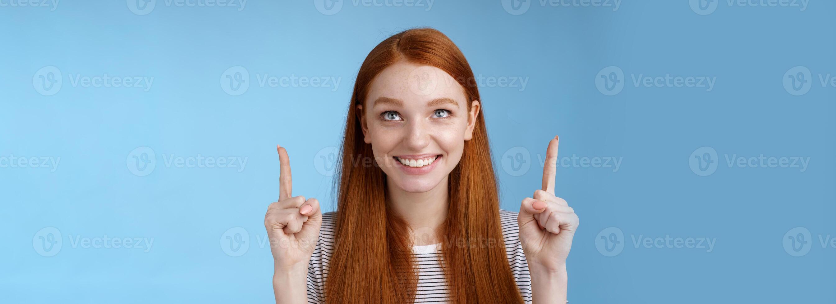 vrolijk nieuwsgierig geamuseerd gelukkig vermaakt roodharige mooi meisje staren richten omhoog glimlachen goedkeuring Leuk vinden interessant Product aan het kijken prestatie genieten koel vakantie promo's, staand blauw achtergrond foto