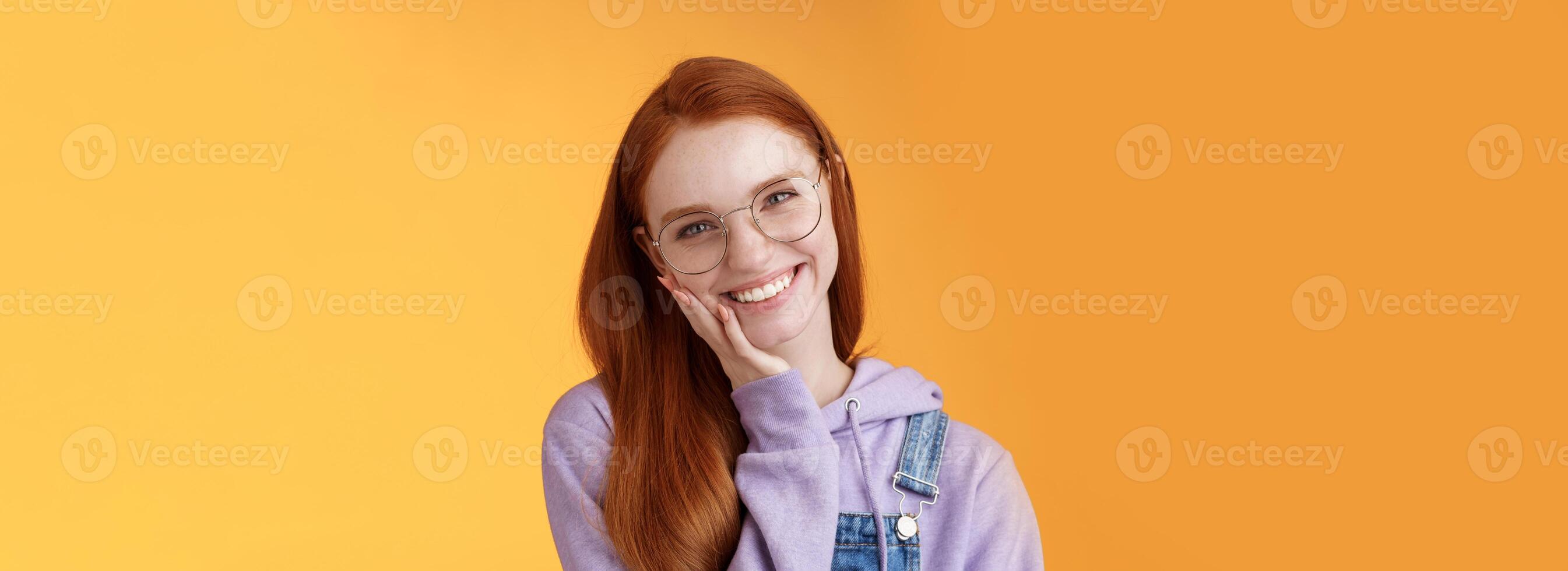 glimlachen tevreden gelukkig roodharige meisje krijgen ontdoen acne verheugd aanraken zacht schoon huid lachend blij pratend voelen vertrouwen zelfverzekerd eigen schoonheid, staand oranje achtergrond genieten communicatie foto