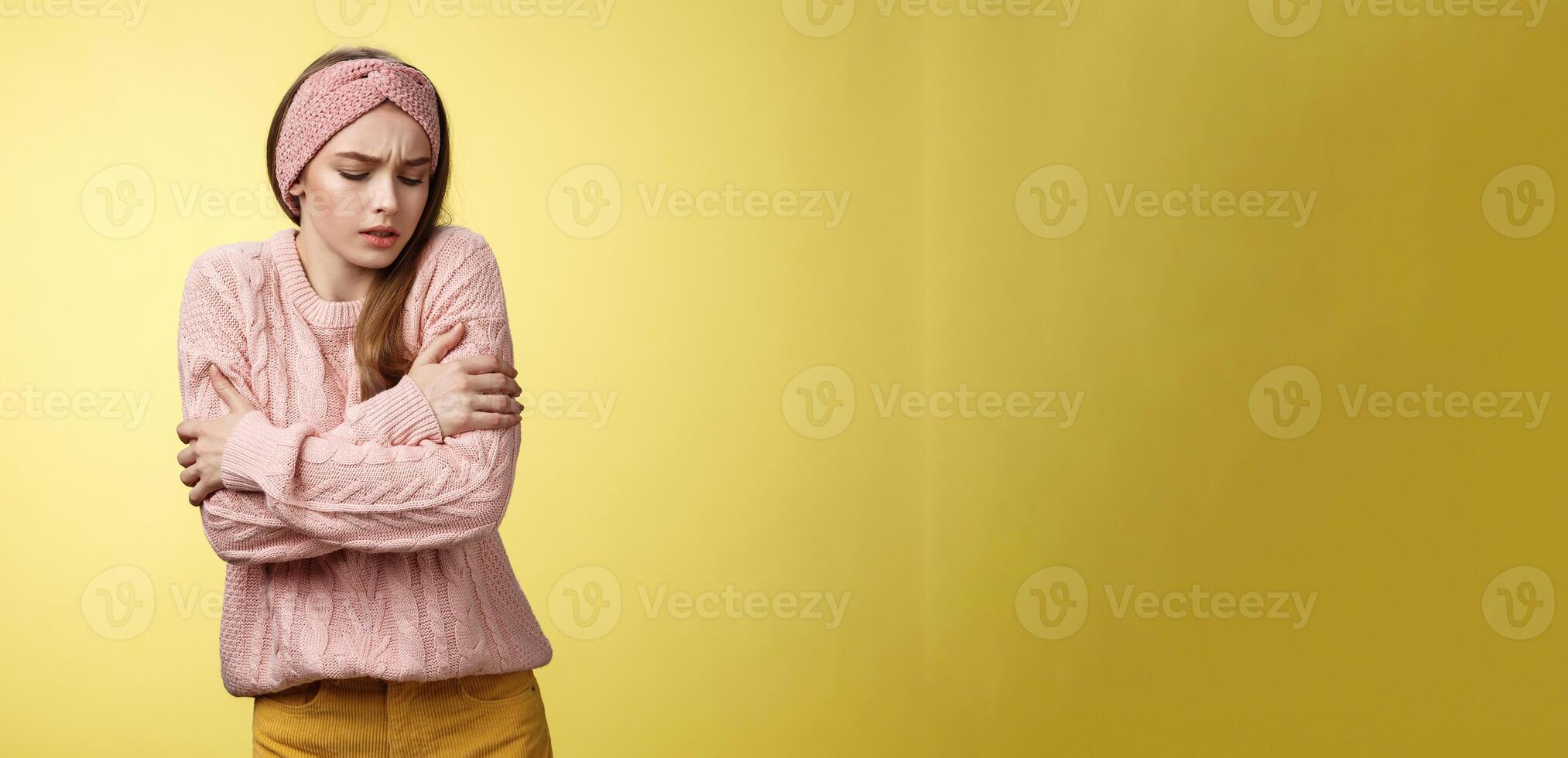 br meisje ijskoud, aanzetten verwarming. portret van timide schattig vrouw vervelend gebreid trui beven van koud, omarmen haarzelf Aan armen op zoek omlaag, bukken van ongemak koel temperatuur foto