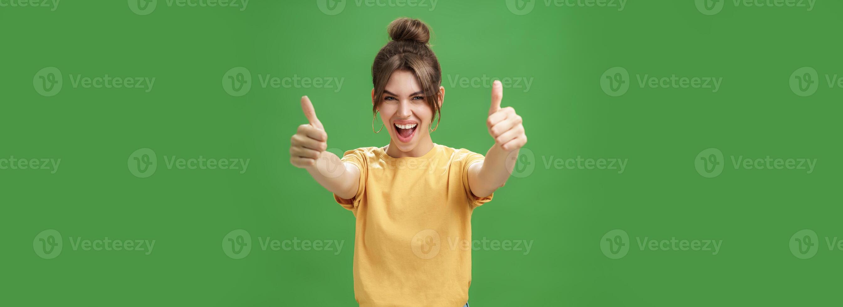 portret van vrolijk enthousiast en opgewonden emotioneel mooi Europese vrouw in geel t-shirt trekken handen met duimen omhoog naar camera glimlachen breed, wezen ondersteunend, leuk vinden idee foto