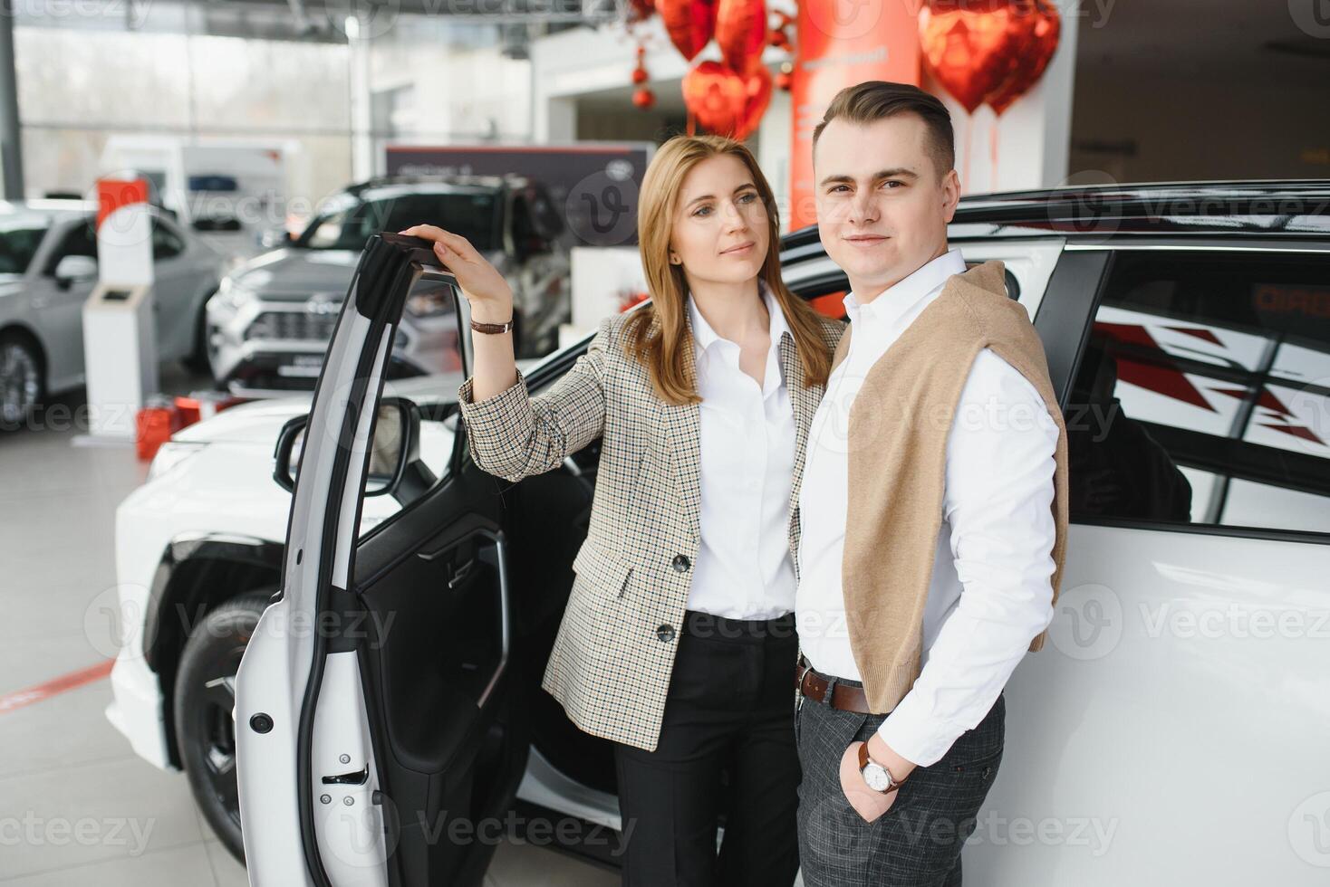 gelukkig jong paar kiest en buying een nieuw auto voor de familie in de handel foto