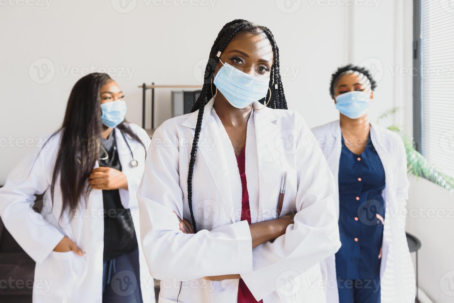 groep van Afrikaanse Amerikaans vrouw artsen in beschermend maskers Aan hun gezichten. foto