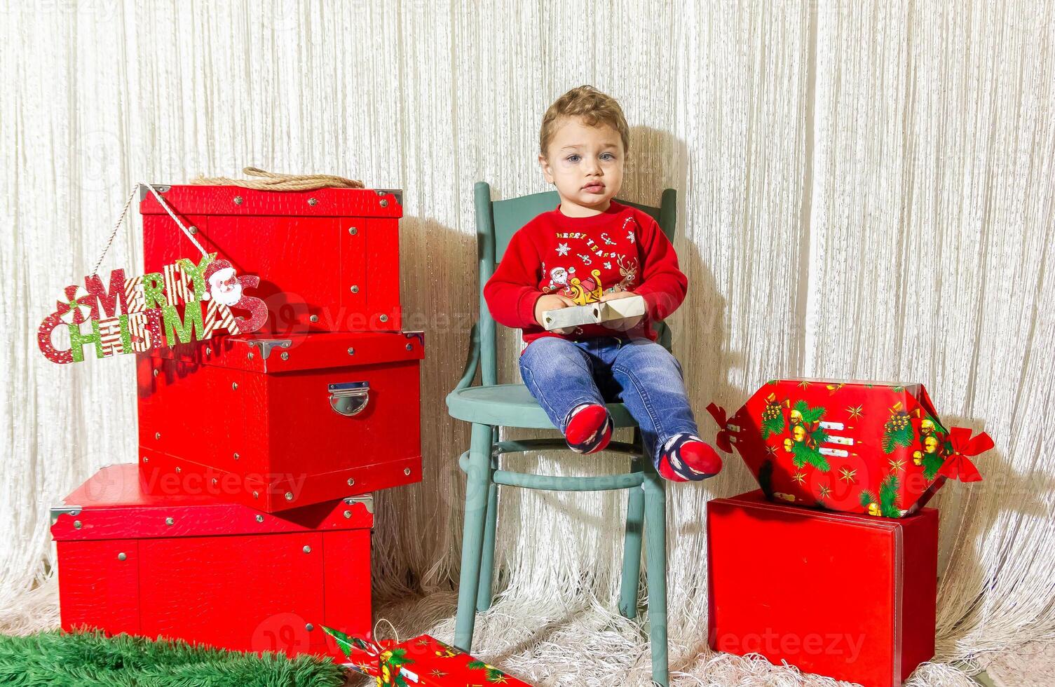 de weinig kind spelen met Kerstmis decoraties in studio, weinig kind met Kerstmis bal foto