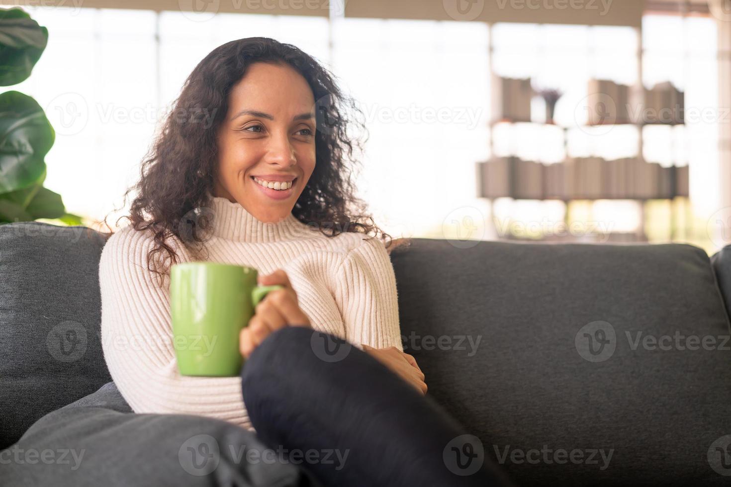 Latijnse vrouw die koffie drinkt op de bank foto