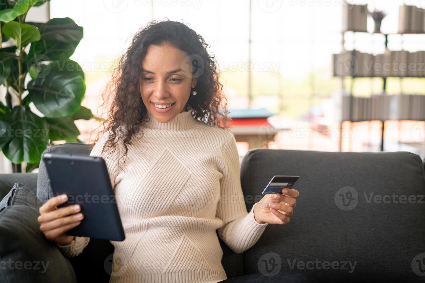 Latijnse vrouw met behulp van tablet en hand met creditcard foto