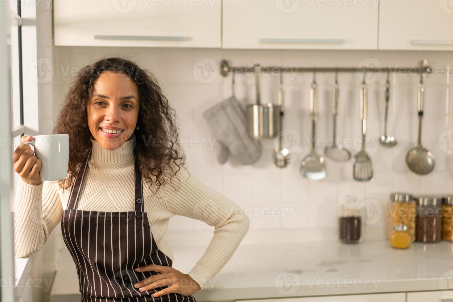 Latijnse vrouw die koffie drinkt in de keuken foto