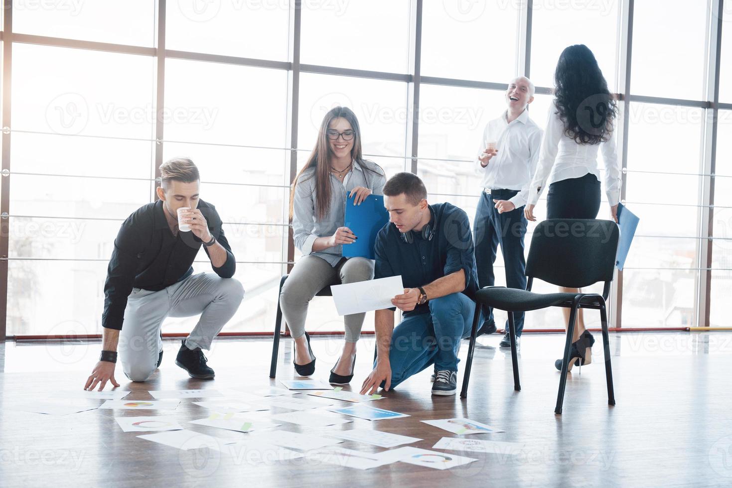 planningsstrategie samen. business team kijkt naar papieren op de vloer op zoek naar één idee. samenwerking zakelijke prestatie en teamwork concept foto