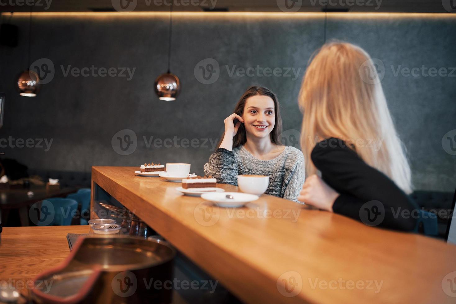 twee vrienden die samen koffie drinken in een koffiebar terwijl ze aan een tafel zitten te kletsen foto