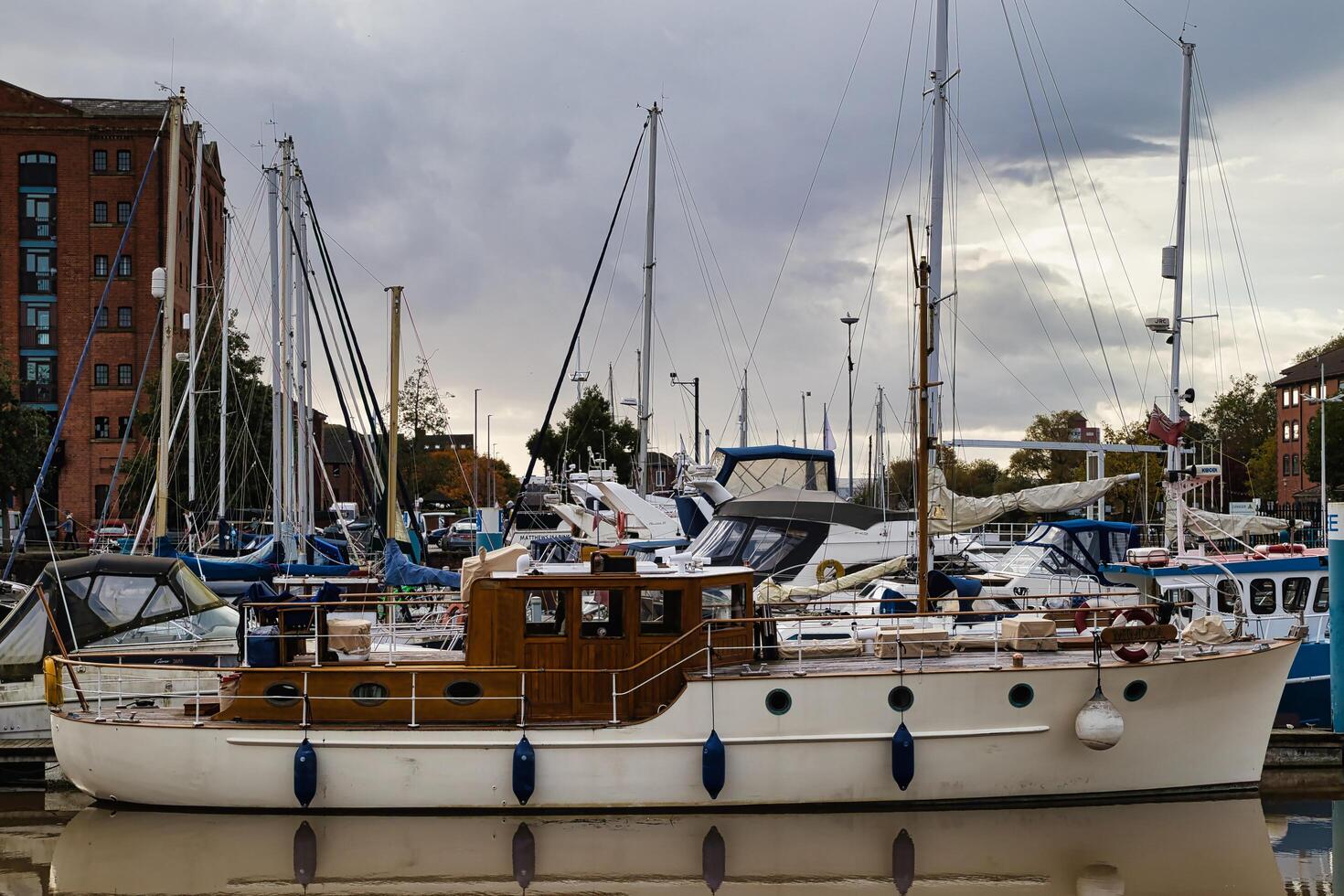 jachthaven met divers zeilboten en jachten aangemeerd Aan een bewolkt dag, met gebouwen in de achtergrond. foto