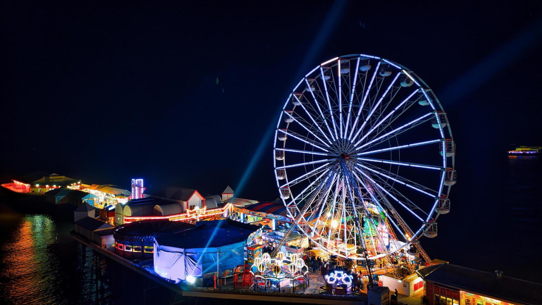 verlichte ferris wiel Bij een nacht eerlijk met levendig lichten en feestelijk atmosfeer in achterpool, Engeland. foto