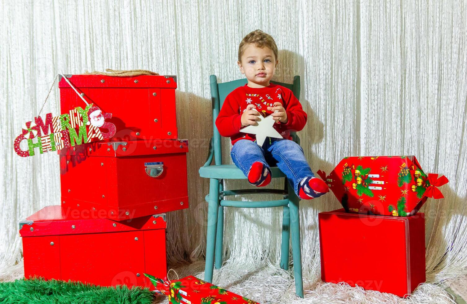 de weinig kind spelen met Kerstmis decoraties in studio, weinig kind met Kerstmis bal foto