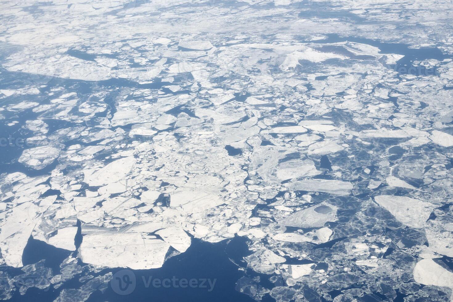 antenne visie van vliegtuig venster over- wolken top naar sneeuw gedekt bevroren zee, winter vers ijzig lucht foto