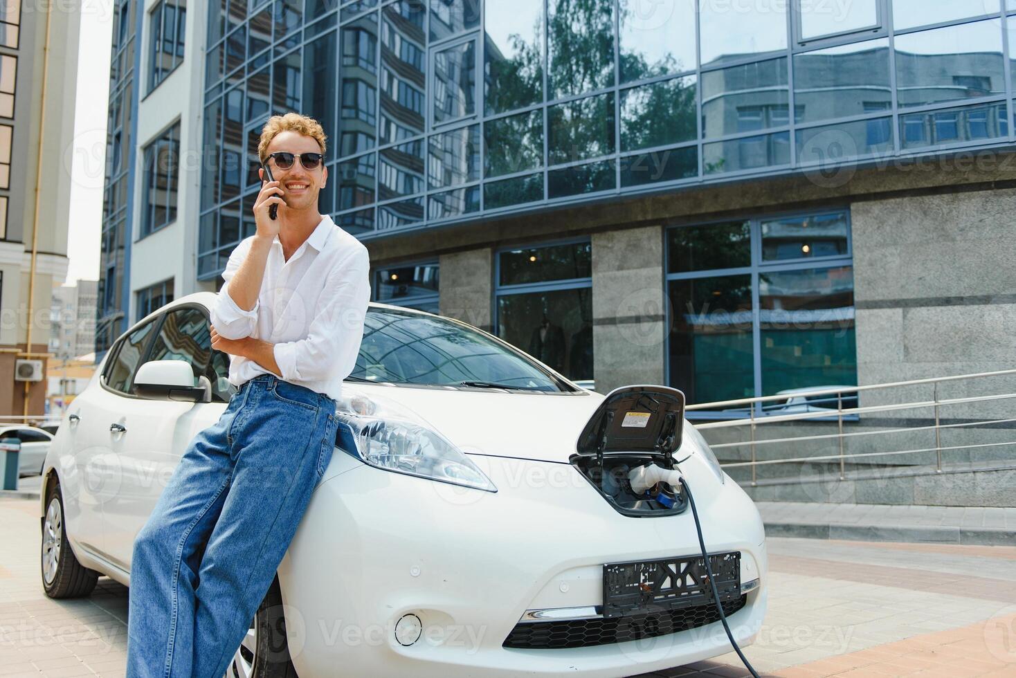 knap Mens gebruik makend van telefoon terwijl auto wezen opgeladen foto