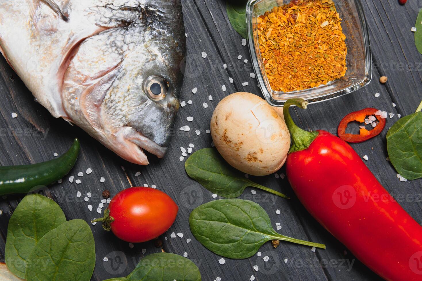 vers rauw dorado vis Aan bakken papier met citroen, peper, tomaten en divers specerijen Aan houten achtergrond met kopiëren ruimte. foto