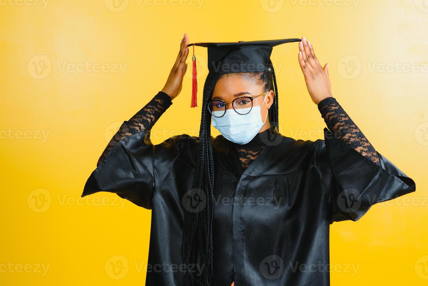 portret van een jong Afrikaanse leerling in een afstuderen pet beschermend masker, Aan een geel achtergrond, diploma uitreiking 2021 foto