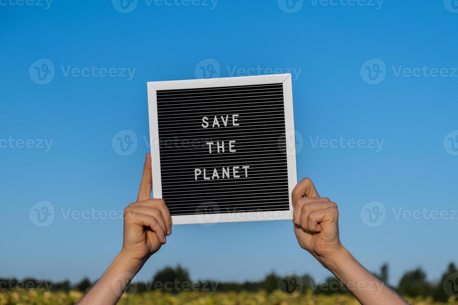 onherkenbaar persoon met banier bericht opslaan de planeet in zonnebloem veld- Aan zonnig dag. teken aarde dag. concept van ecologie en eco activisme milieu problemen hou op globaal opwarming. Gaan groen duurzame foto