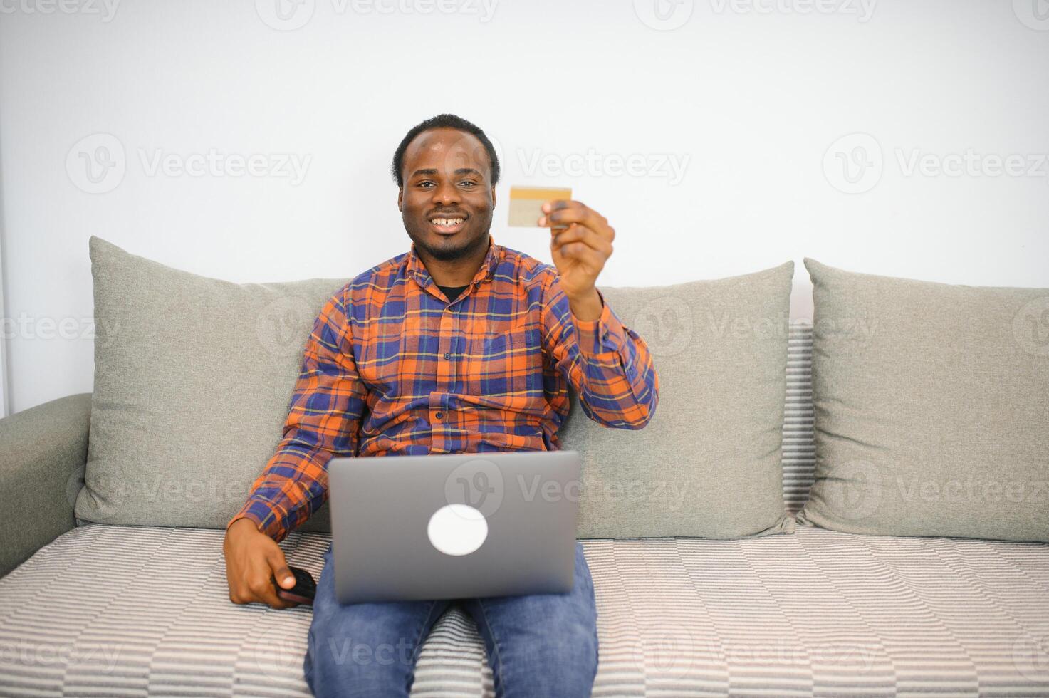 jong Afrikaanse Mens Holding credit kaart en tablet Bij huis foto
