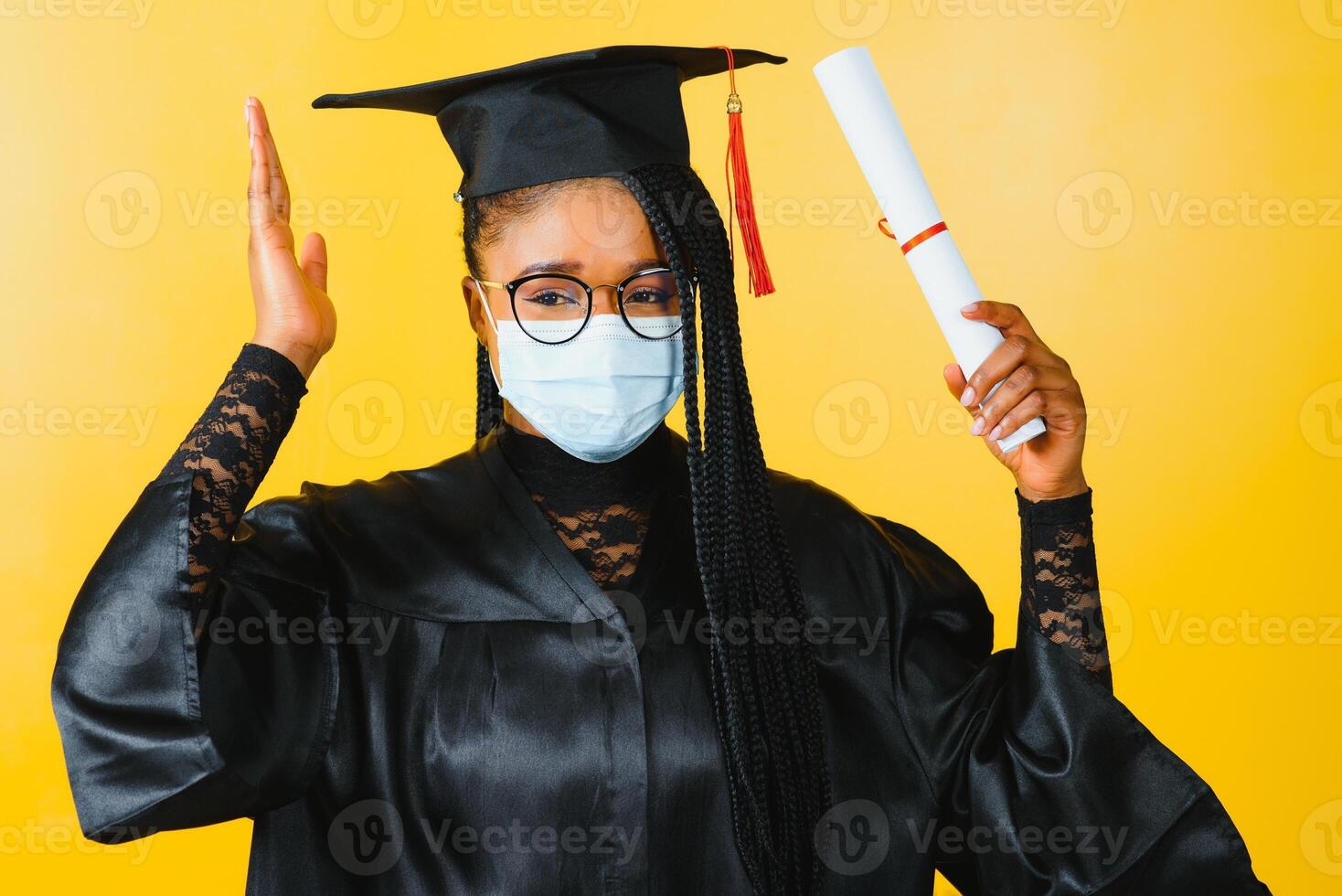 portret van een jong Afrikaanse leerling in een afstuderen pet beschermend masker, Aan een geel achtergrond, diploma uitreiking 2021 foto