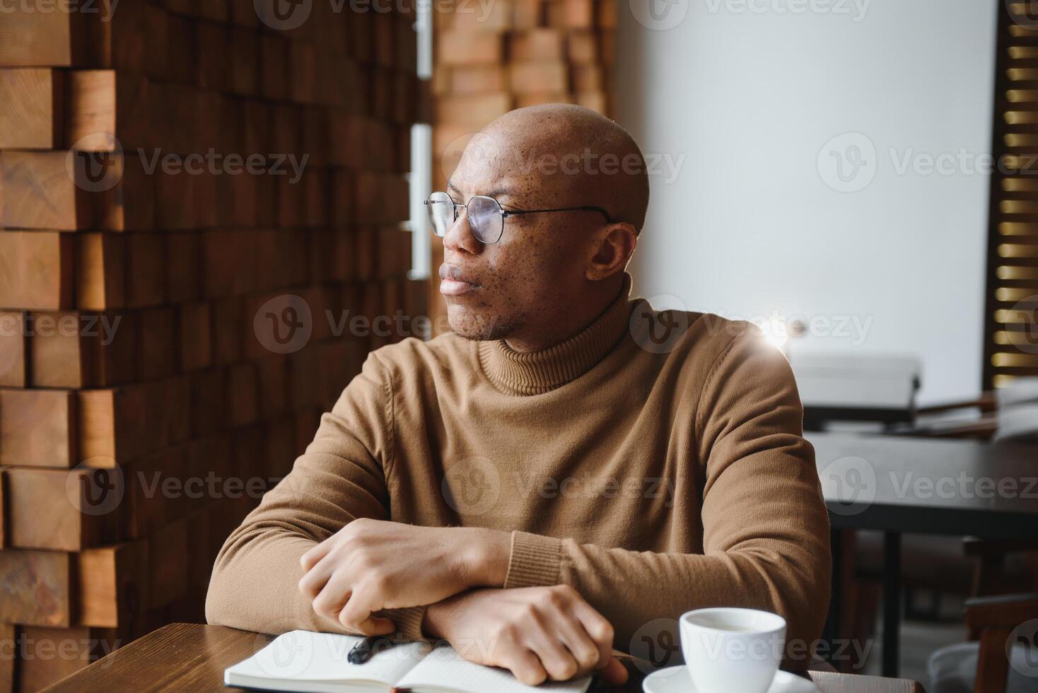 geconcentreerd zwart mannetje ondernemer leest papier documenten zittend in cafe met koffie in de buurt venster foto