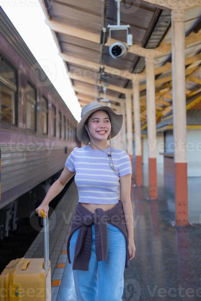 jong vrouw met koffer wacht Bij de metro station terwijl de trein arriveert, toerisme en reizen in de zomer. vakanties voor de leerling. werk en reizen foto
